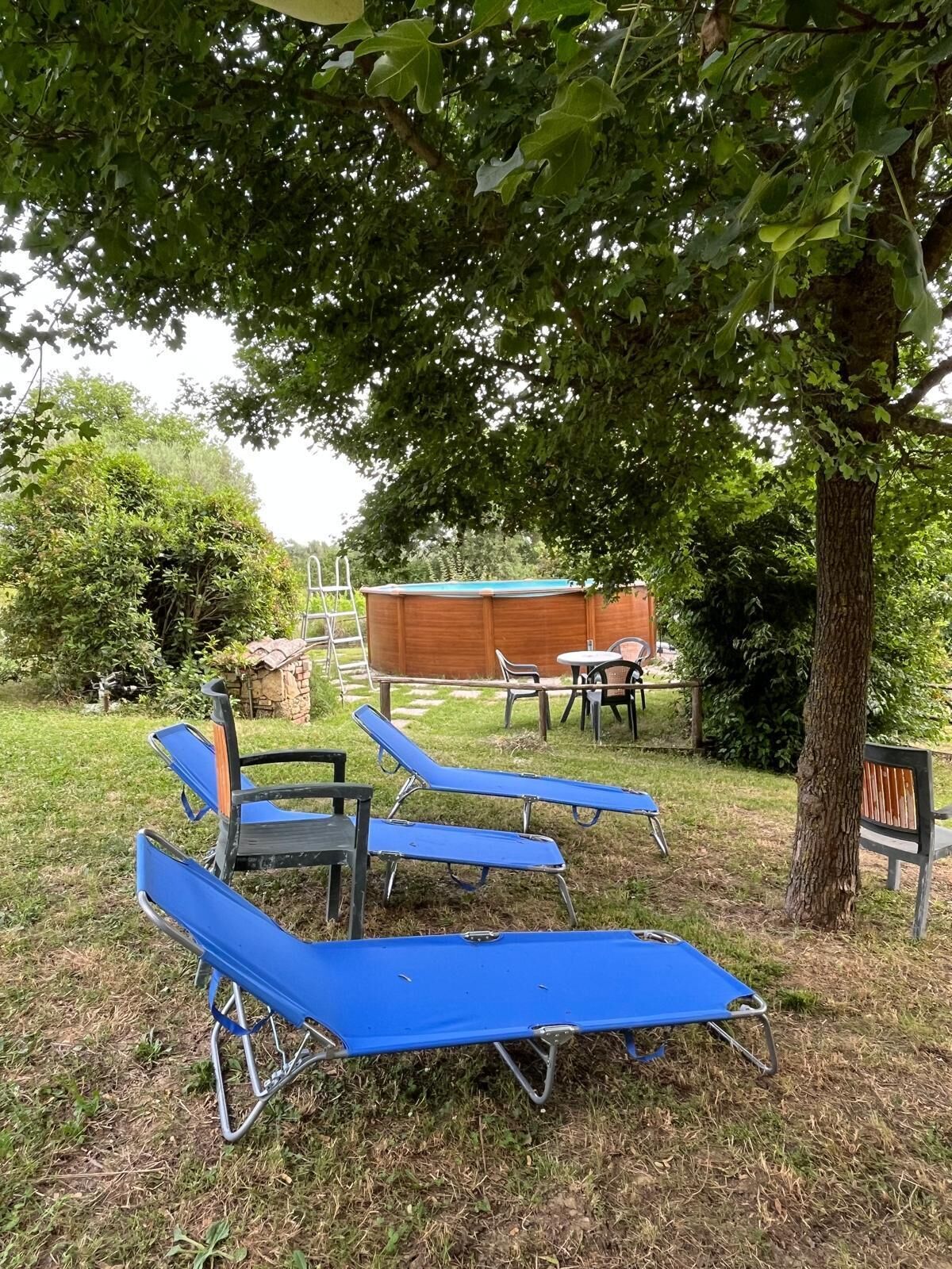 A backyard with a wooden deck, a table and chairs, and a blue lounge chair.
