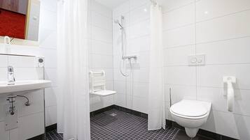 Uma casa de banho moderna com chuveiro, sanita e lavatório.