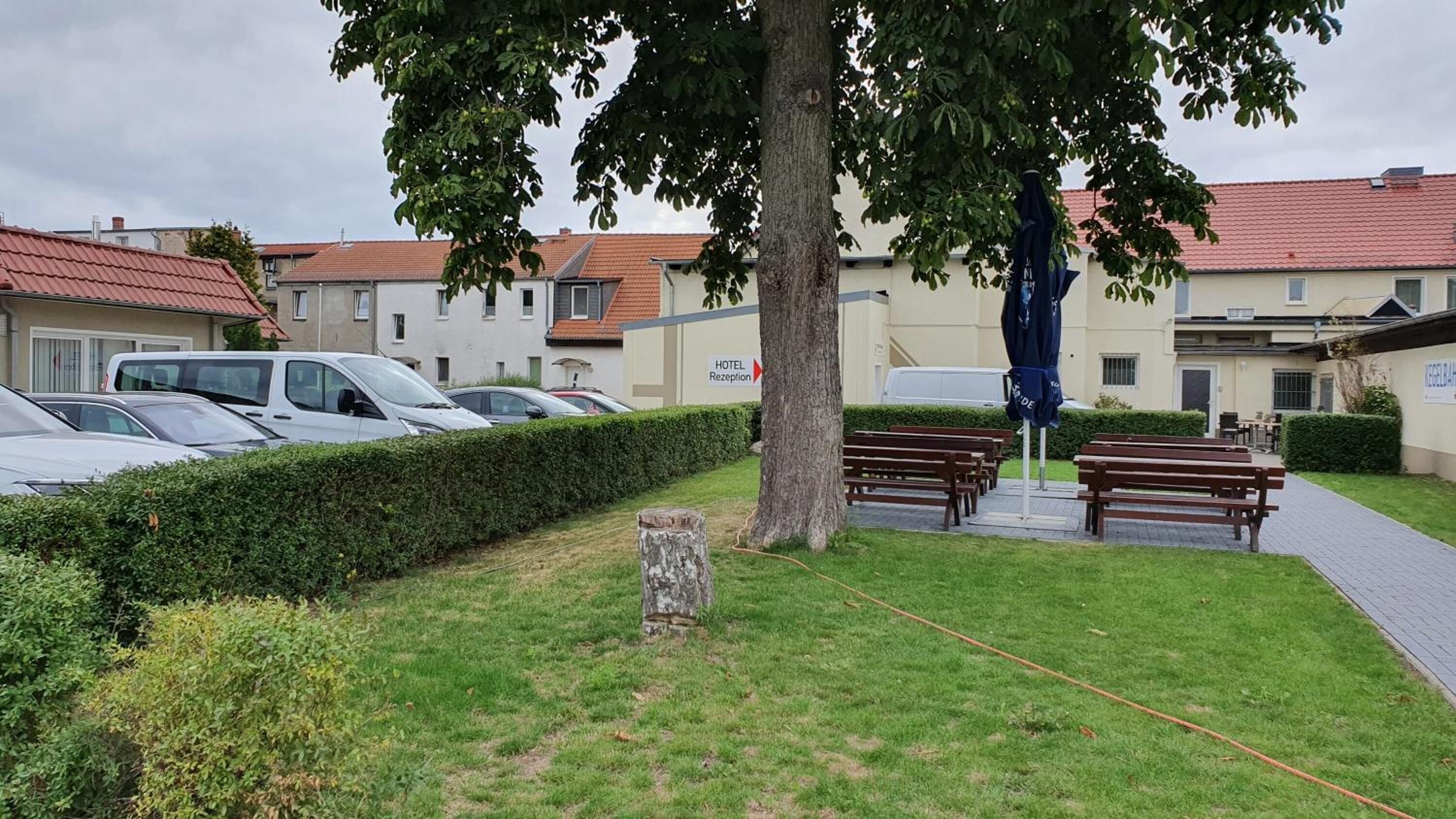 Een hotel receptie met een boom, banken en geparkeerde auto's.