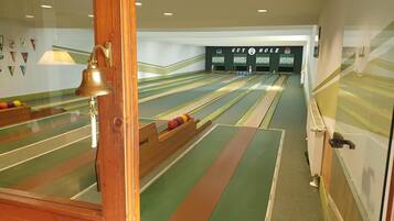 Un bowling doté de nombreuses pistes, d’une vitrine en bois où sont exposés des trophées, et d’un mur sur lequel on peut lire l’inscription « GUT HOLZ ».