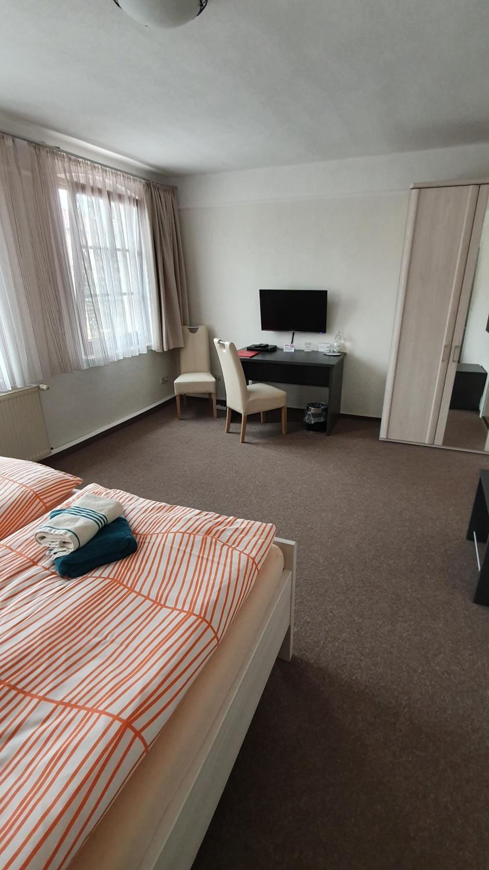 Una habitación de hotel con una cama, un escritorio con computadora, una silla y un televisor.