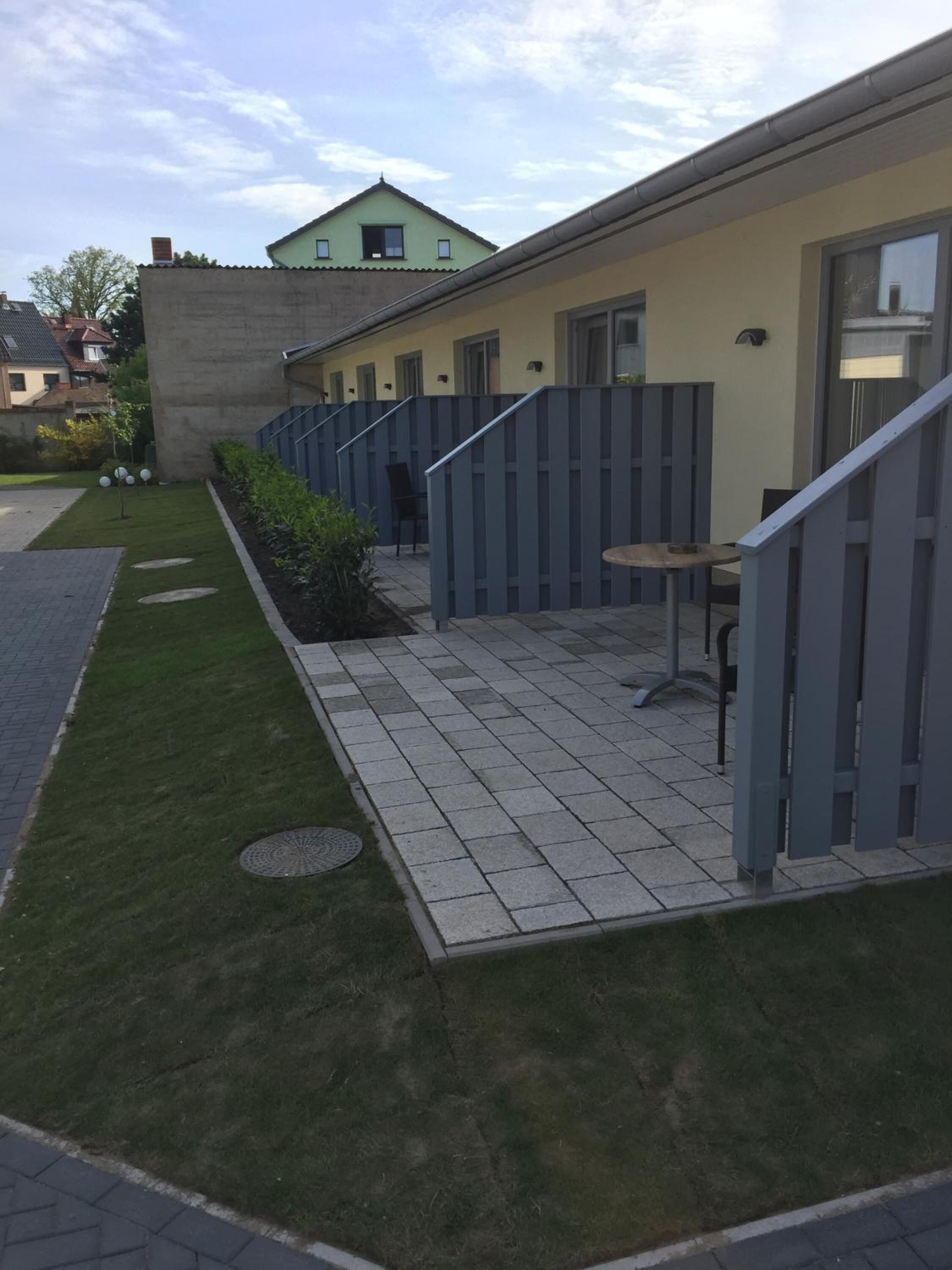 A courtyard with a paved walkway, a small seating area, and a building with a green roof.