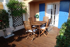 A wooden deck with a table and chairs, a blue door, and a garden wall. - house / villa - SAINT-CYPRIEN (Saint-Cyprien)