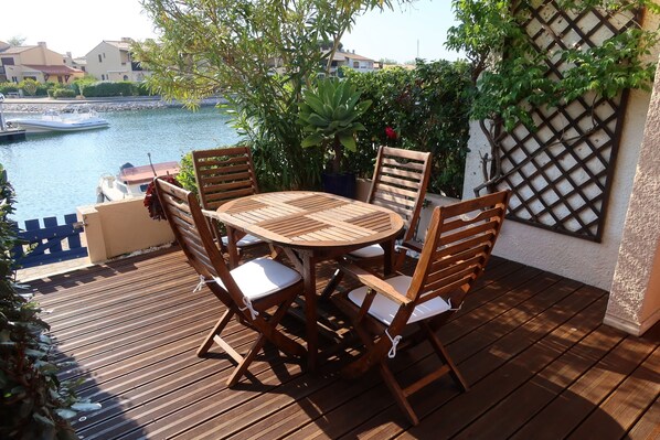 A wooden deck with a round table and chairs, overlooking a body of water with boats. - house / villa - SAINT-CYPRIEN (Saint-Cyprien)
