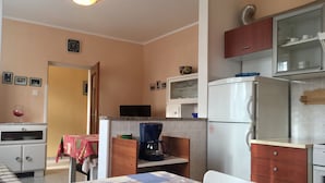 A compact kitchen with a refrigerator, microwave, and coffee maker. There is a dining table with a quilted tablecloth.