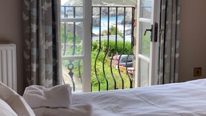 Ein Schlafzimmer mit einem Bett, weißen Handtüchern und Blick auf eine Küstenlandschaft durch ein offenes Fenster.
