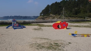 A sandy beach with playground equipment, including a blue slide and a red and yellow climbing structure. - house on garden, decorated by a painter, Pont Aven with 9kmwallo (Moëlan-Sur-Mer)