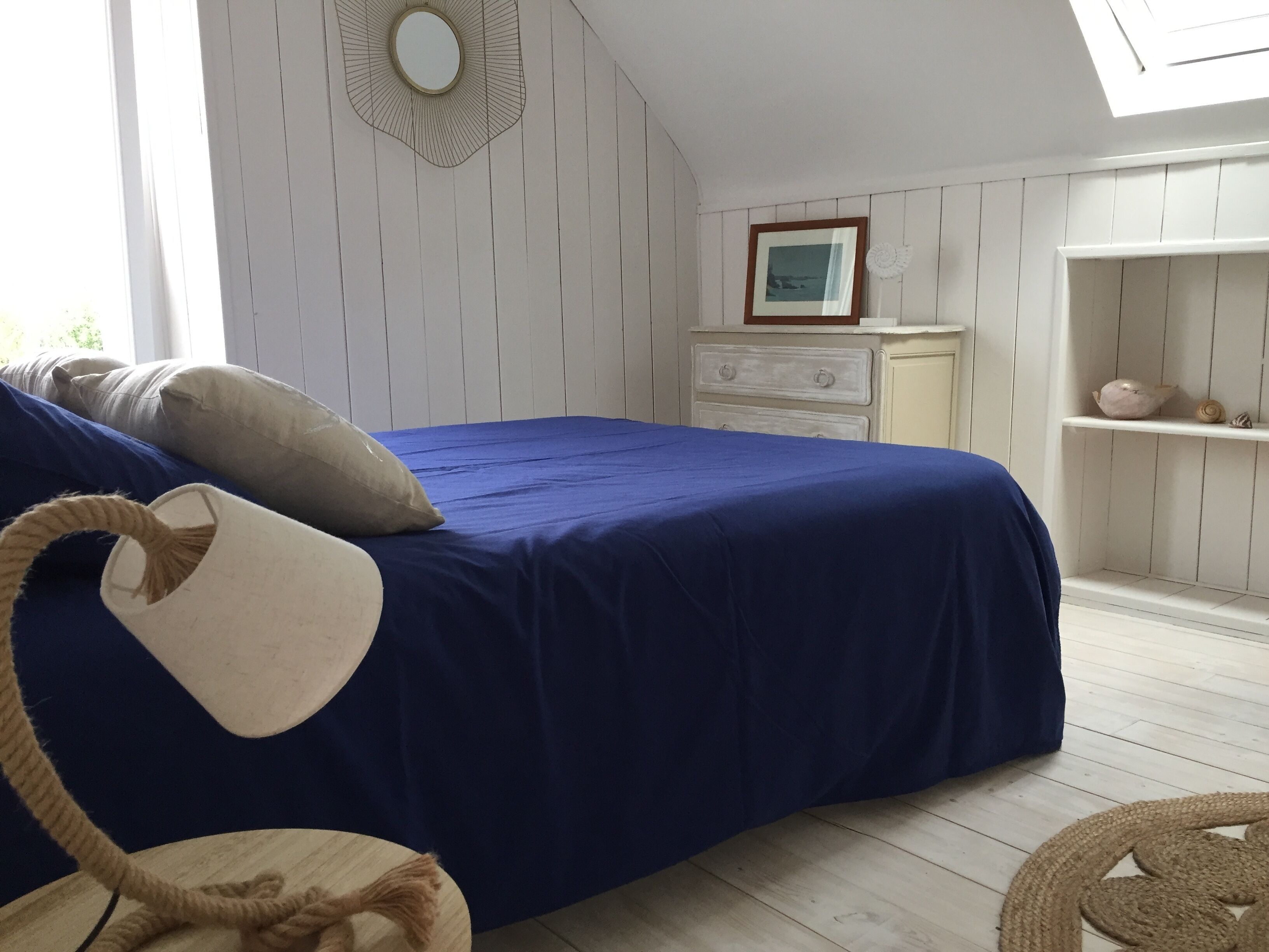 A bedroom with a blue bedspread, a white dresser, and a cat tree.