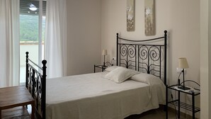 Een slaapkamer met een bed, twee wandlampen, een plafondventilator en een raam met gordijnen.