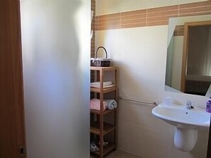 A bathroom with a wooden shelf, a sink, and a mirror.