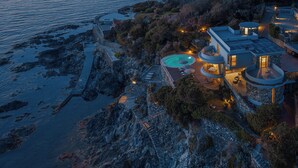 A modern coastal property with a pool, outdoor seating, and a view of the sea. - House / Villa - Castiglioncello(LI) (Castiglioncello)