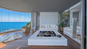 A modern living room with a large window overlooking the ocean, a white sofa, and a coffee table with decorative items. - House / Villa - Castiglioncello(LI) (Castiglioncello)