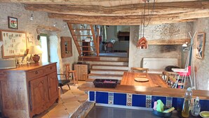 A rustic kitchen with wooden cabinets, a tiled backsplash, and a wooden dining table.