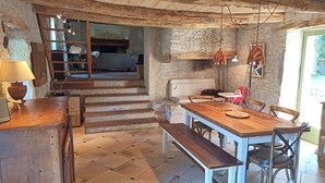 A rustic interior with a wooden dining table, benches, and a staircase leading to another room.