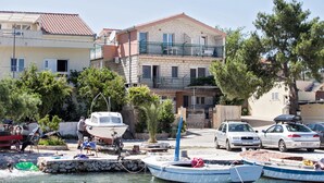 A coastal building with a balcony, parked cars, and boats docked at a marina. - Villa Stana (Marina)