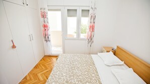 A bedroom with a bed, wooden wardrobe, and a window with curtains. - Villa Stana (Marina)