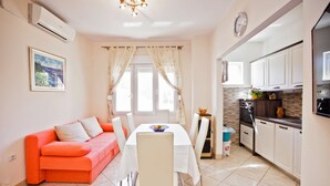 A modern kitchen with white cabinets, a built-in oven, and a countertop with a vase and fruits. - Villa Stana (Marina)
