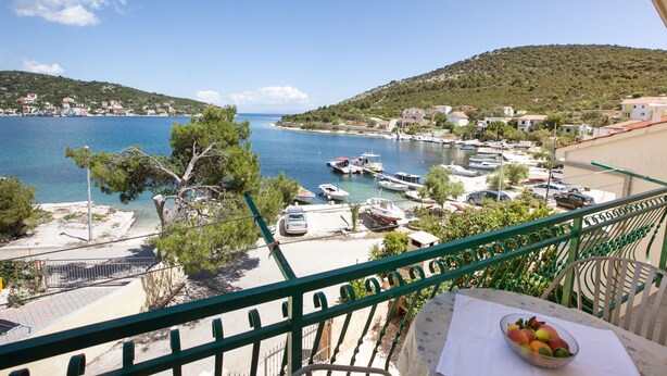 A balcony with a view of a coastal town, a marina with boats, and a table with fruit. - Villa Stana (Marina)