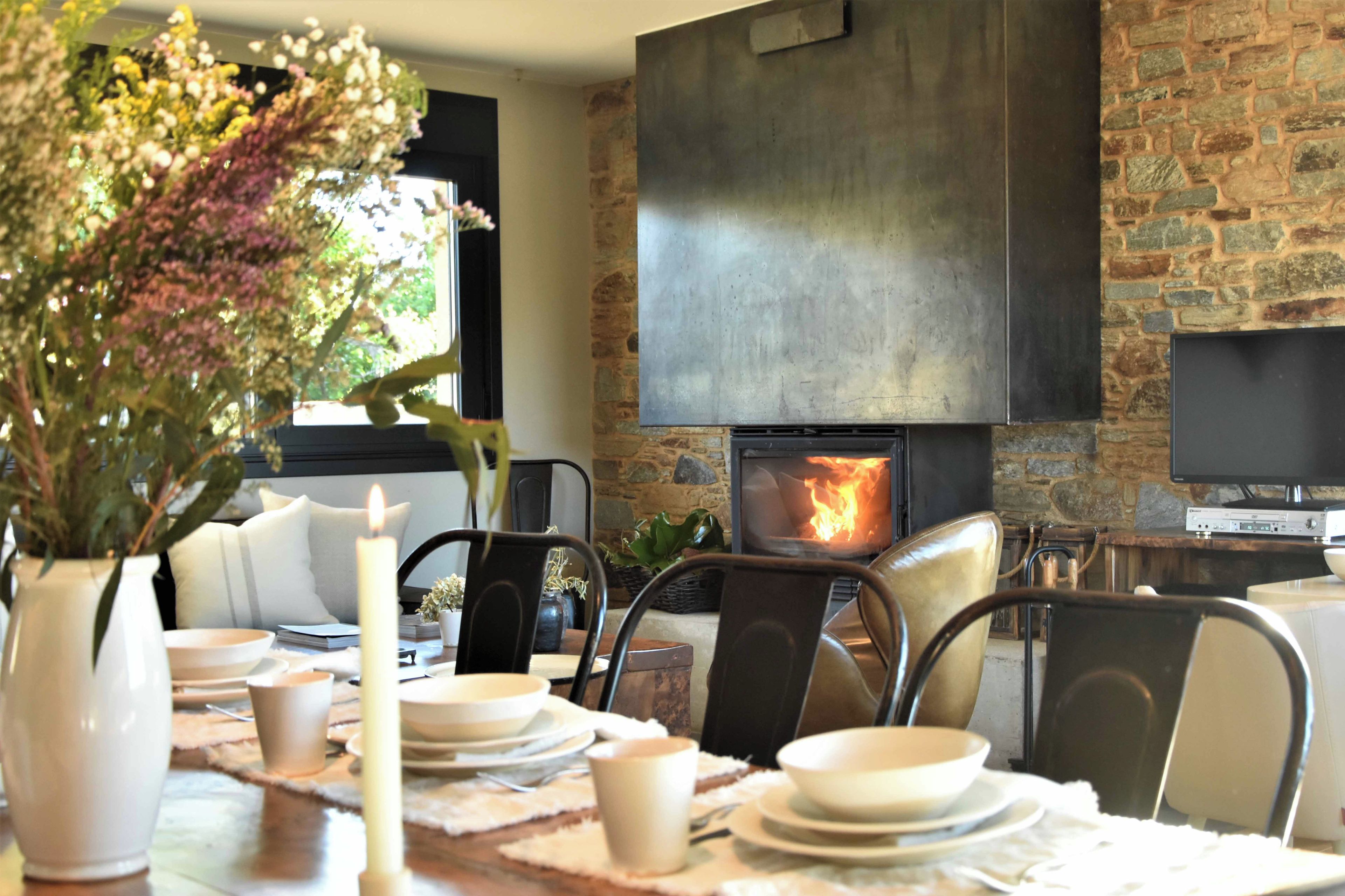 Un comedor con chimenea de piedra, televisor y una mesa dispuesta para cuatro.
