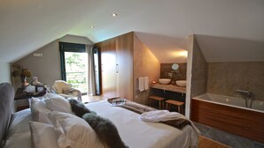 Quarto moderno com cama grande, banheiro com banheira e vista para o exterior.