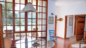 Ein Zimmer mit Glastisch, blauen Stühlen und einem großen Fenster mit Blick ins Freie.