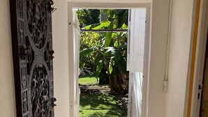Un couloir agrémenté d’une porte décorative et donnant sur un jardin.