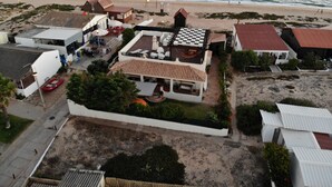 A coastal property with multiple buildings, a beach view, and a patio area with outdoor seating.