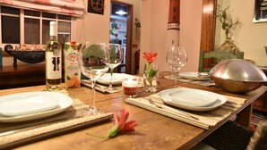 A dining table set with plates, glasses, and a bottle of wine, with a decorative wall and a lighthouse model in the background.