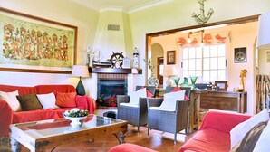 A living room with a fireplace, red furniture, and nautical decor.