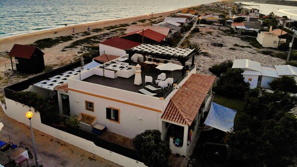 A coastal building with multiple rooms, a patio area, and a view of the beach and ocean.
