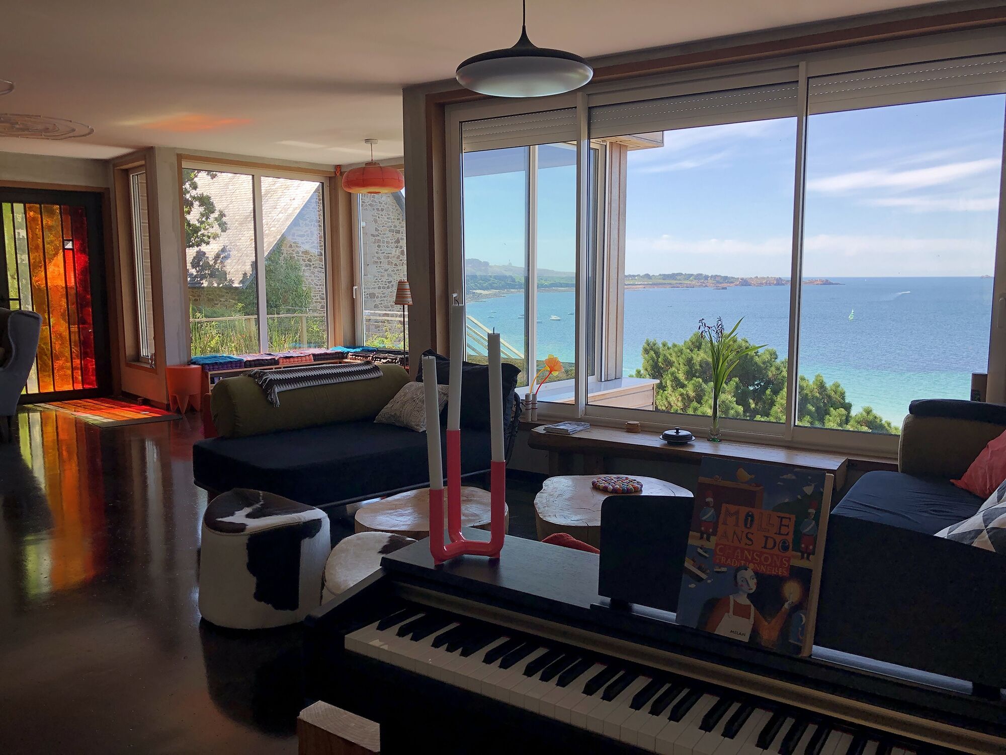 Un salon chaleureux avec un piano, un canapé et une vue sur la mer.