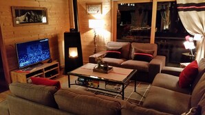Ein gemütliches Wohnzimmer mit Fernseher, Kamin und einer Couch.