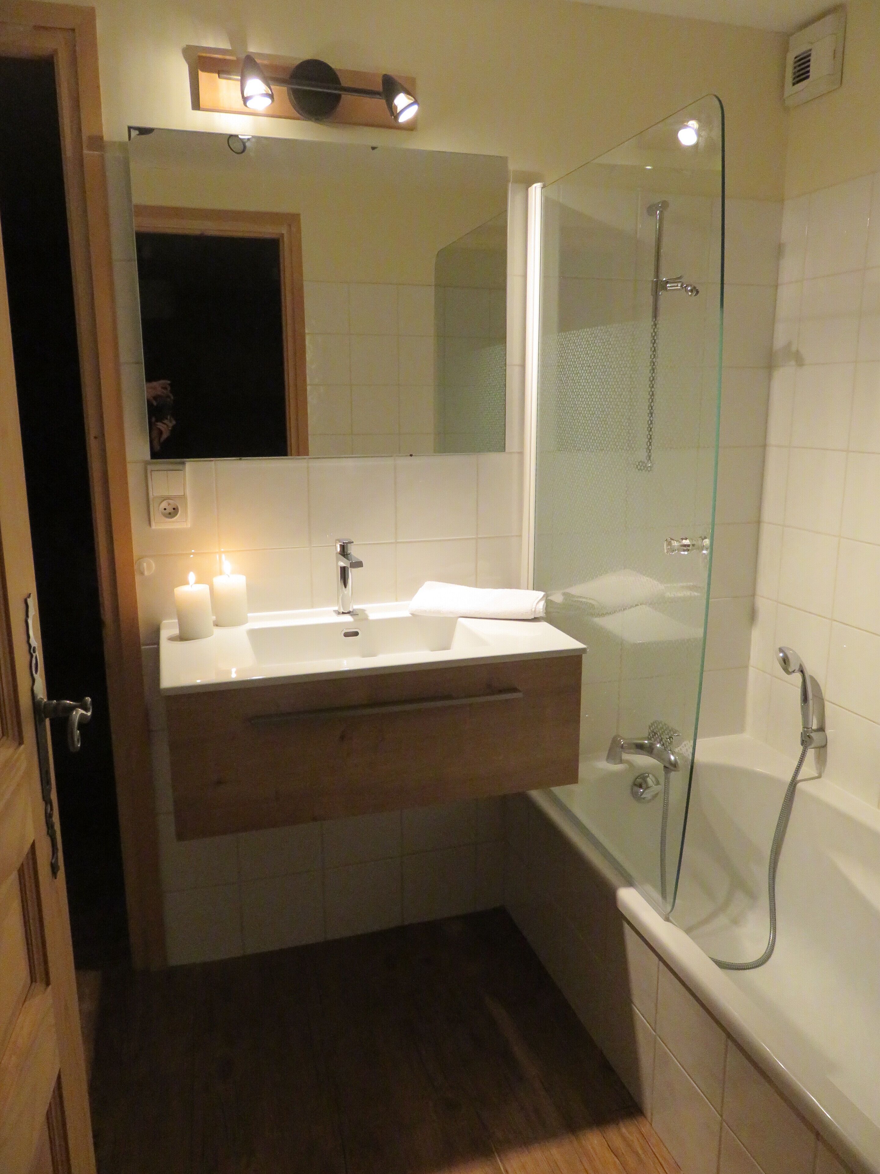 A modern bathroom with a glass-enclosed shower, a vanity with a mirror, and a wooden cabinet.