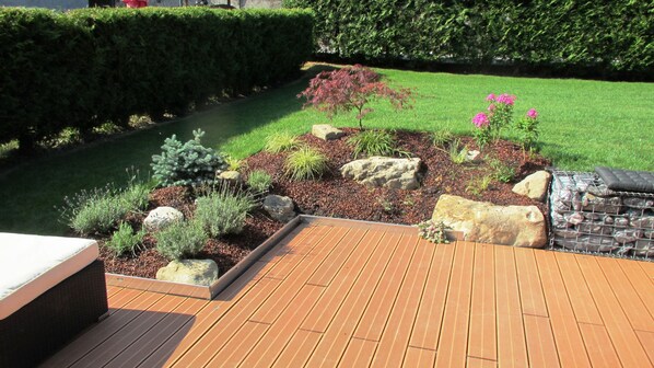 A wooden deck with a garden area featuring rocks, shrubs, and a small flower bed.