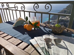 A wooden table with a blue tablecloth, two oranges, a glass of orange juice, a wicker basket with succulents, and a newspaper. - HOUSE WITH PRIVATE PARKING AND MAGNIFICENT VIEW ON THE BAY OF POSITANO (Positano)