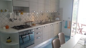 Eine moderne Küche mit Gasherd, Backofen und Spüle. Es gibt Schränke, eine Arbeitsplatte und einen Essbereich mit Tisch und Stühlen.
