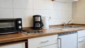 Une cuisine compacte équipée d’un four à micro-ondes, d’une machine à café et d’un évier.
