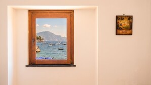 A window with a view of boats on water, a wooden door, and a framed picture on the wall. - Casa della Marina · Historic beachfront tonnara with direct sea access (Conca dei Marini)