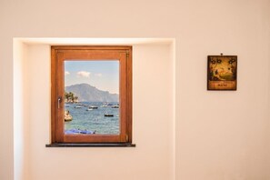 A window with a coastal view, a framed picture of Jamaica rum, and a wooden door.