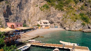 A coastal building with a dock, boats, and a rocky cliff. - Casa della Marina · Historic beachfront tonnara with direct sea access (Conca dei Marini)