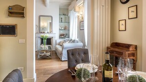 Un coin repas avec une table en bois dressée pour deux personnes, une bouteille de vin et des verres à vin vides.
