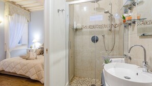 Une chambre avec un lit, une douche en verre et une salle de bain avec un lavabo.