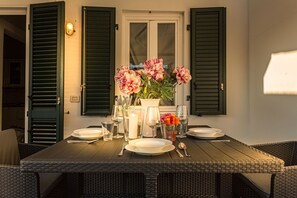 An outdoor dining area with a table set for four, surrounded by wicker chairs. - 2 Bedrooms 2 Bathrooms Romantic Apartment with Terrace and Parking in Lucca (Lucca)