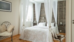 Une chambre à coucher avec un lit à baldaquin, un plancher en bois et une couvre-lit blanche.