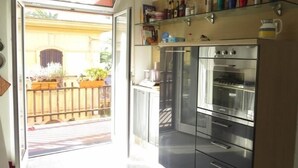 A modern kitchen with stainless steel appliances, a glass door leading to a balcony, and a variety of kitchenware on shelves. - Bright, spacious, terraces, one step from the sea, high-speed wifi, Cinqueterre (Sestri Levante)