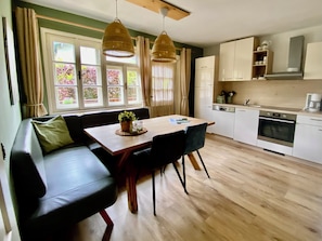 A modern kitchen with white cabinets, a built-in oven, and a dining area with a wooden table and black chairs.