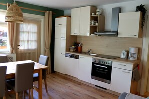 Une cuisine compacte comprenant une table à manger, des chaises, un lave-vaisselle, un four et une machine à café.