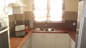 A compact kitchen with white cabinets, a wooden countertop, a built-in oven, a sink, and a refrigerator. - Comfortable Villa Close to Lake Sea Mountains Airport Unrivaled View  (Prades)