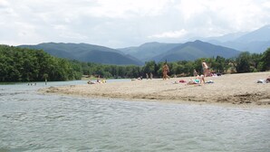 A beach with people sunbathing and swimming, surrounded by mountains and greenery. - Comfortable Villa Close to Lake Sea Mountains Airport Unrivaled View  (Prades)
