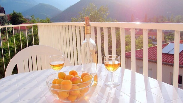 A table with a bowl of fruit and two glasses of wine on a balcony with a mountain view. - Comfortable Villa Close to Lake Sea Mountains Airport Unrivaled View  (Prades)